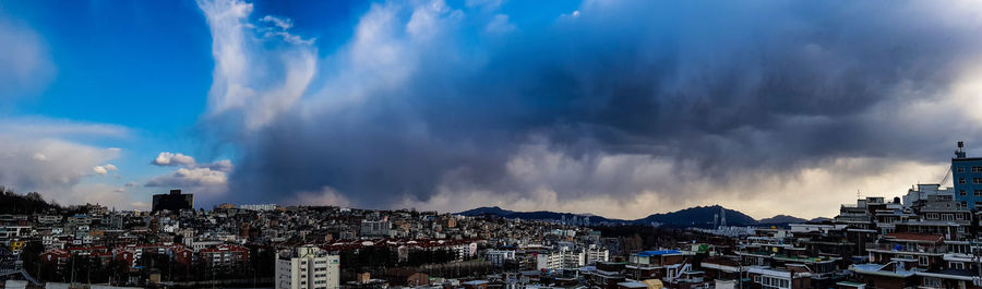 Panoramic view of buildings against cloudy sky