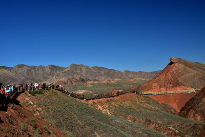 Group of people on mountain range against clear blue sky, zhangye danxia national geological park 