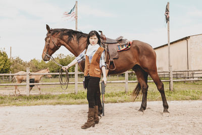 Portrait of woman standing with horse at ranch