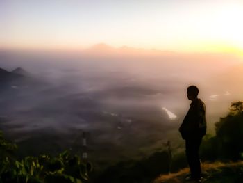 Silhouette man standing on mountain against sky during sunset