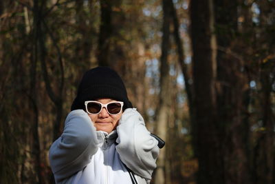 Portrait of woman wearing sunglasses standing in forest