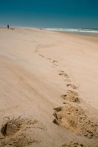 Steps on white sand with clear sky next to the ocean