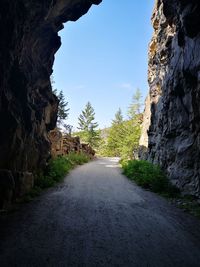 Empty road amidst rocks against clear sky