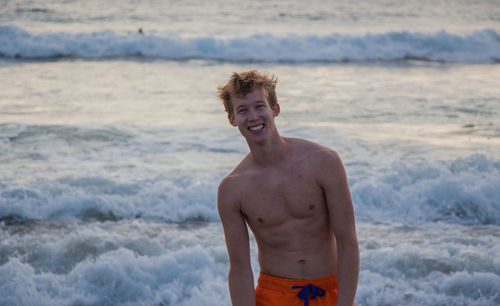 Portrait of shirtless man standing at beach