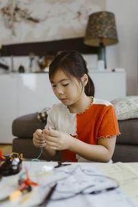 Focused girl preparing science project sitting at home