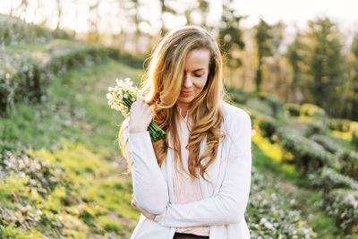 Adorable woman in a spring landscape with a bouquet of snowdrops.