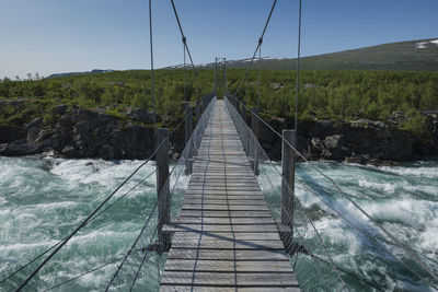 Footbridge over land against sky