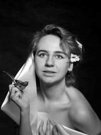 Portrait of female model holding flower over black background
