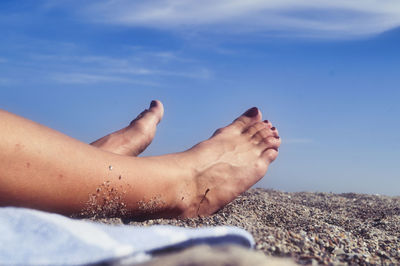 Low section of woman on beach against sky