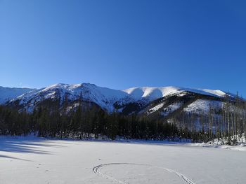 Scenic view of snowcapped mountains against clear blue sky