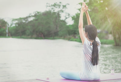 Rear view of woman with practicing yoga at lakeshore