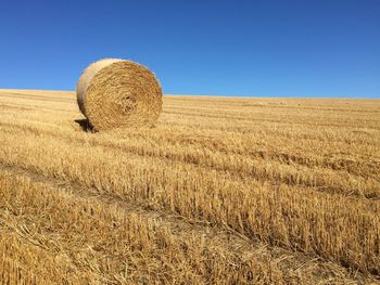 Hay bales on field against clear sky