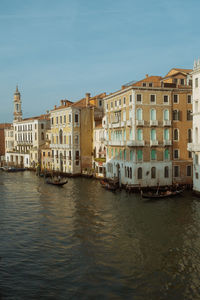 Buildings by river against sky