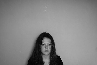 Portrait of young woman standing against wall