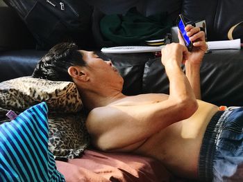 Mature man using mobile phone while resting at home