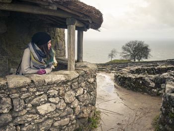 Woman wearing warm clothing while standing in gazebo against sea