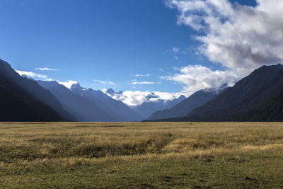 Scenic view of landscape and mountains against blue sky