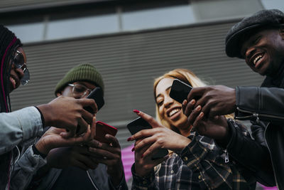 Black friends using smartphones on street