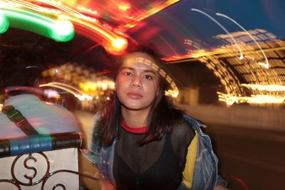 Portrait of woman in illuminated carousel at night