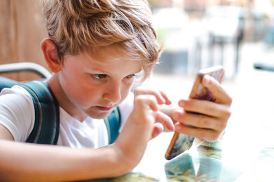 Boy using mobile phone while sitting at restaurant