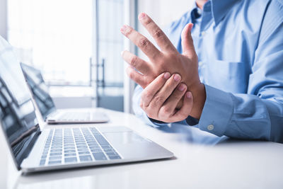 Midsection of man using laptop on table