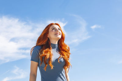 Cute young woman smiling looking at the sky with copy space on an urban street