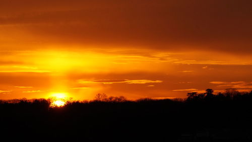 Silhouette landscape against dramatic sky during sunset