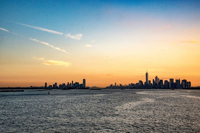 Buildings in city by east river against sky during sunset