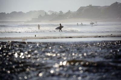 Man with surfboard walking at sea shore