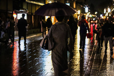 People walking on wet road during rainy season