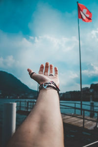 Close-up of hand with bracelet over sea