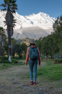 Tourist walks through the town named yungay with the snow-capped huascaran in the background.