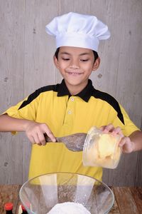 Boy wearing chef hat preparing food in kitchen at home