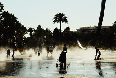 People at wet town square against sky