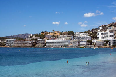 Buildings by swimming pool in sea against blue sky