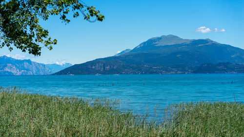 Scenic view of sea and mountains against blue sky