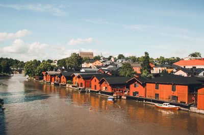 Bridge over river by buildings against sky