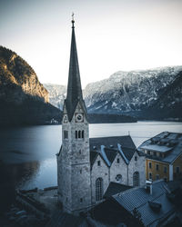 Church by building against sky during winter