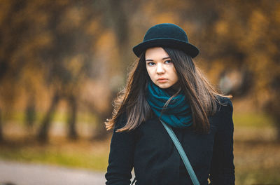 Portrait of young woman standing in park during autumn