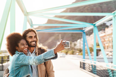 Cheerful woman taking selfie with boyfriend on street