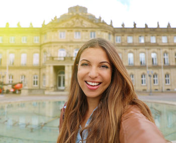 Smiling cheerful young woman in front of neues schloss  of stuttgart, germany.