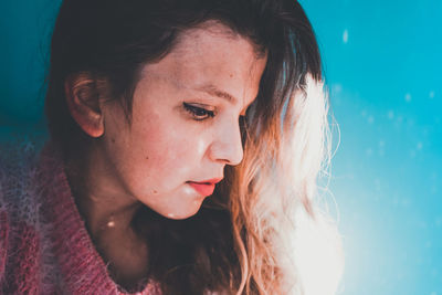 Close-up of young woman against blue wall