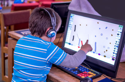 A young boy plays a game on a laptop computer