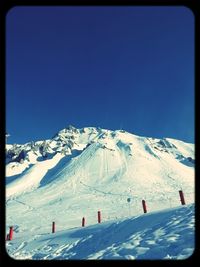 Scenic view of snow covered mountains against clear blue sky