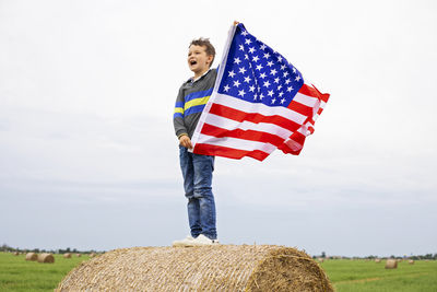 Full length of woman holding american flag against sky