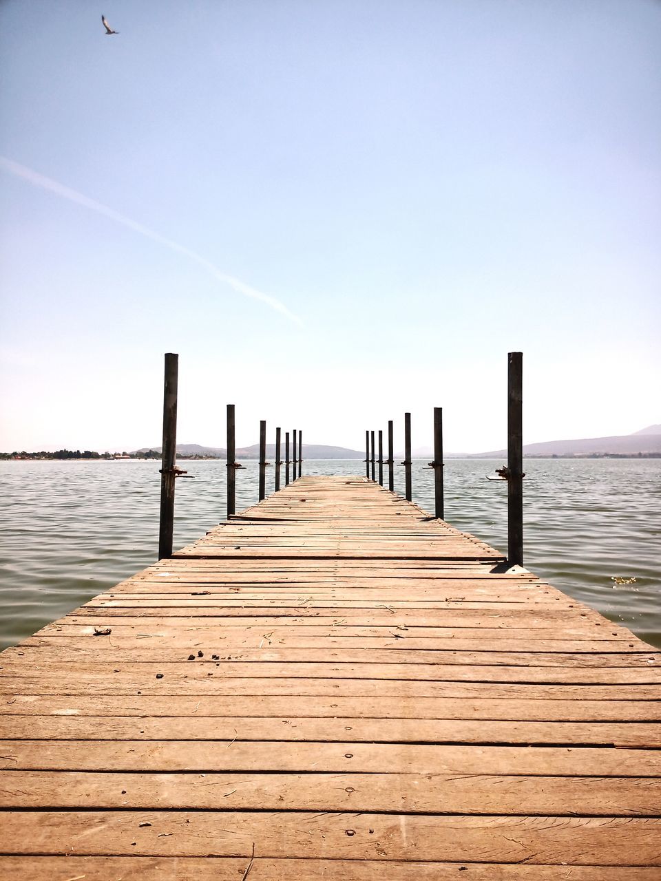 wood, pier, sky, water, horizon, boardwalk, jetty, walkway, nature, sea, tranquility, scenics - nature, beauty in nature, tranquil scene, the way forward, shore, ocean, land, morning, beach, coast, sunlight, landscape, summer, architecture, no people, diminishing perspective, footpath, clear sky, outdoors, dock, horizon over water, day, copy space, reflection, holiday, relaxation, idyllic, wooden post, post, environment, seascape, blue, travel destinations, sunny, urban skyline, built structure, trip, vacation, vanishing point, travel, empty, cloud, non-urban scene, wood paneling, sand