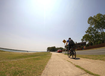 People riding bicycle on road against sky