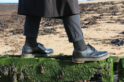 Low section of man standing on mossy rock