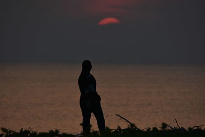 Silhouette man standing on beach against sky during sunset