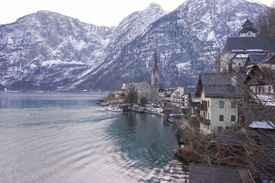 Houses by lake against snowcapped mountains